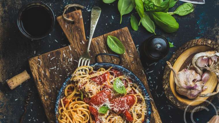A bowl of pasta with tomato sauce and basil.
