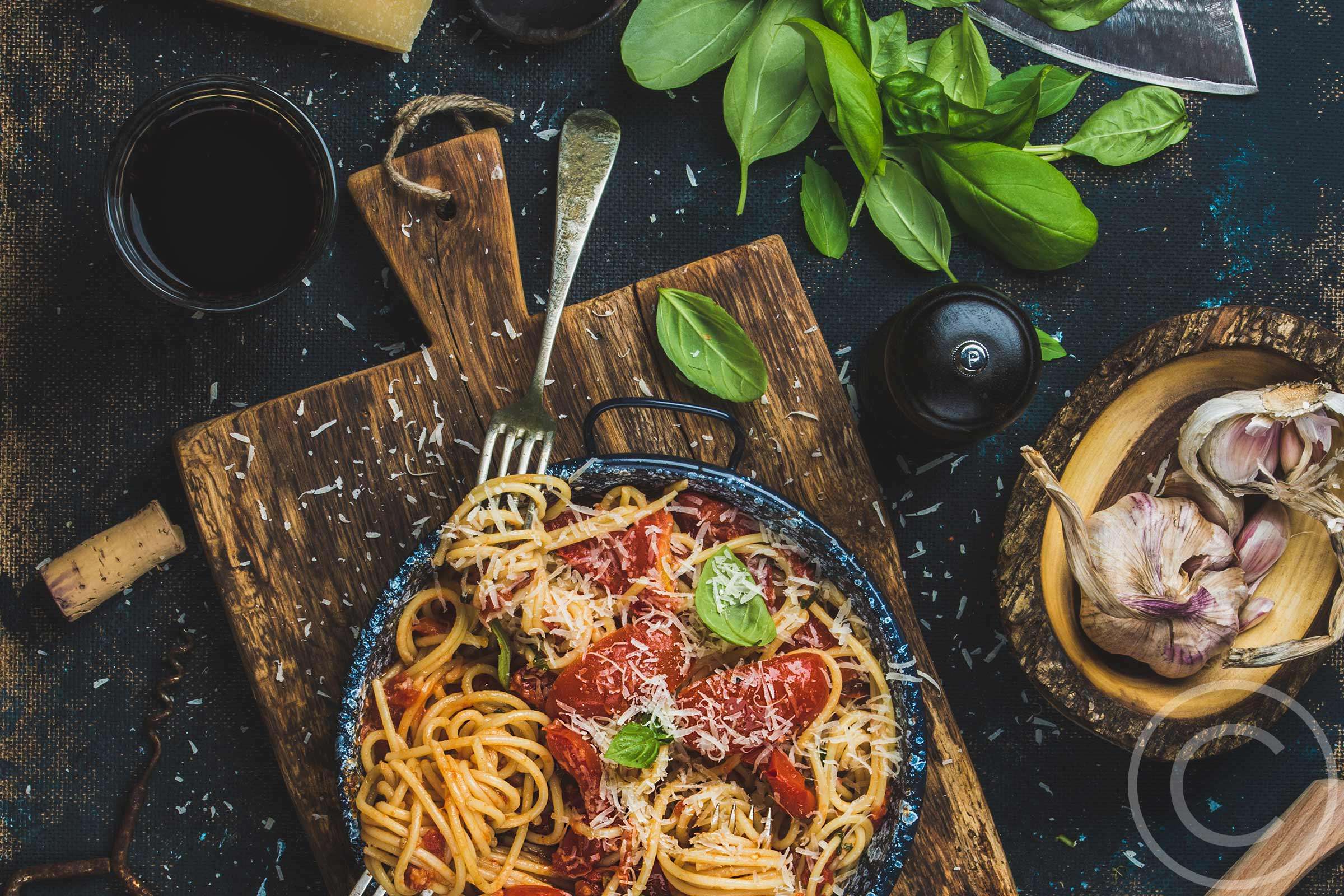 A bowl of pasta with tomato sauce and basil.